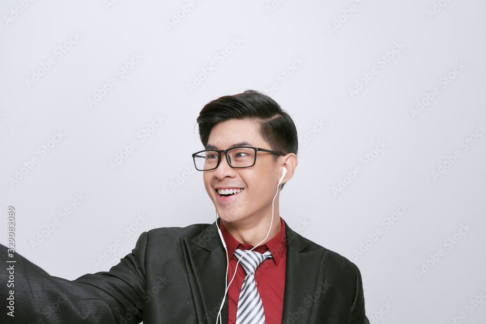 Happy adult man wearing earphones holding mobile phone looks at screen Happy adult man wearing earphones holding mobile phone looks at screen