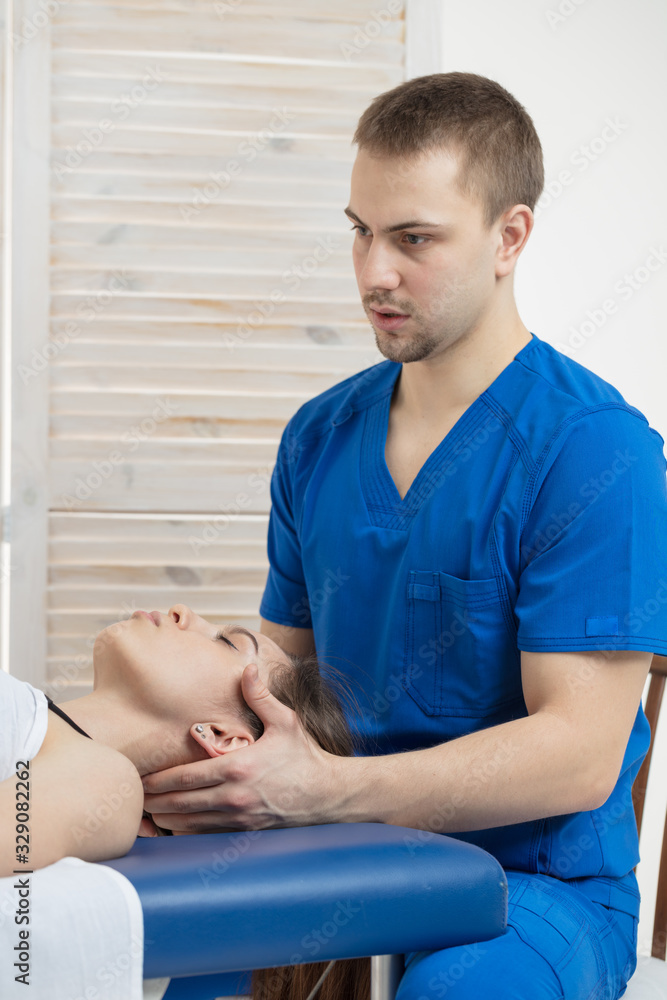 Obraz premium The woman is lying on the couch, and the doctor makes a diagnosis of the occipital part of the head. Manual therapy.
