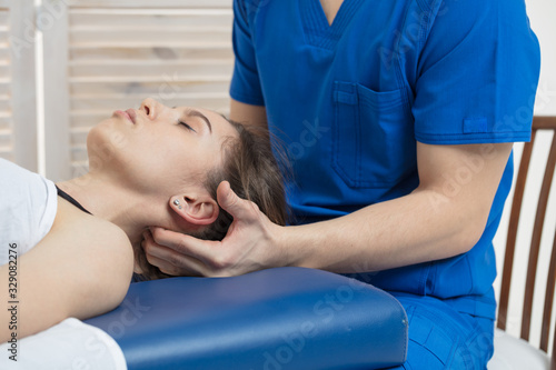 фотографія The woman is lying on the couch, and the doctor makes a diagnosis of the occipital part of the head