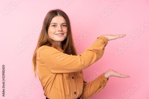 Ukrainian teenager girl over isolated pink background holding copyspace to insert an ad © luismolinero