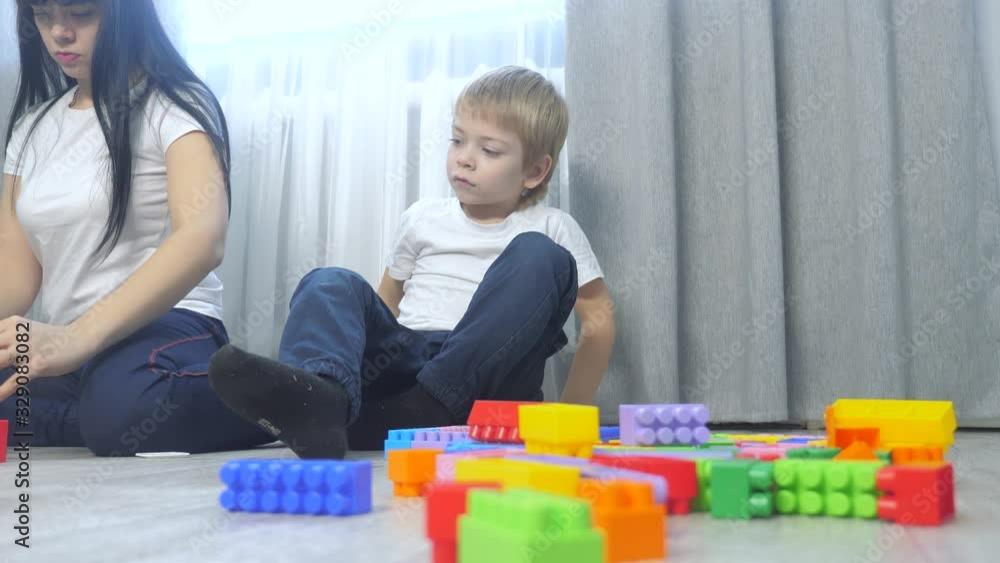 childhood happy family mom lifestyle and children are playing concept little girl and boy brother and sister collects constructor teamwork. child plays toys sitting on floor. children play in team childhood happy family mom lifestyle and children are playing concept little girl and boy brother and sister collects constructor teamwork. child plays toys sitting on floor. children play in team