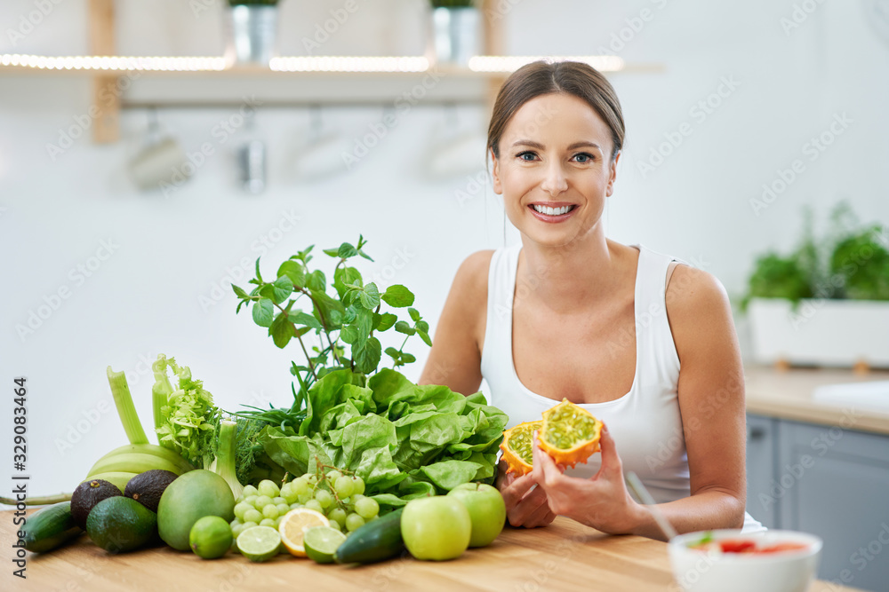 Healthy adult woman with green food in the kitchen