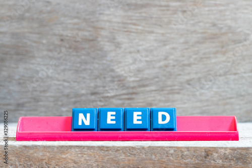 Tile letter on red rack in word need on wood background photo