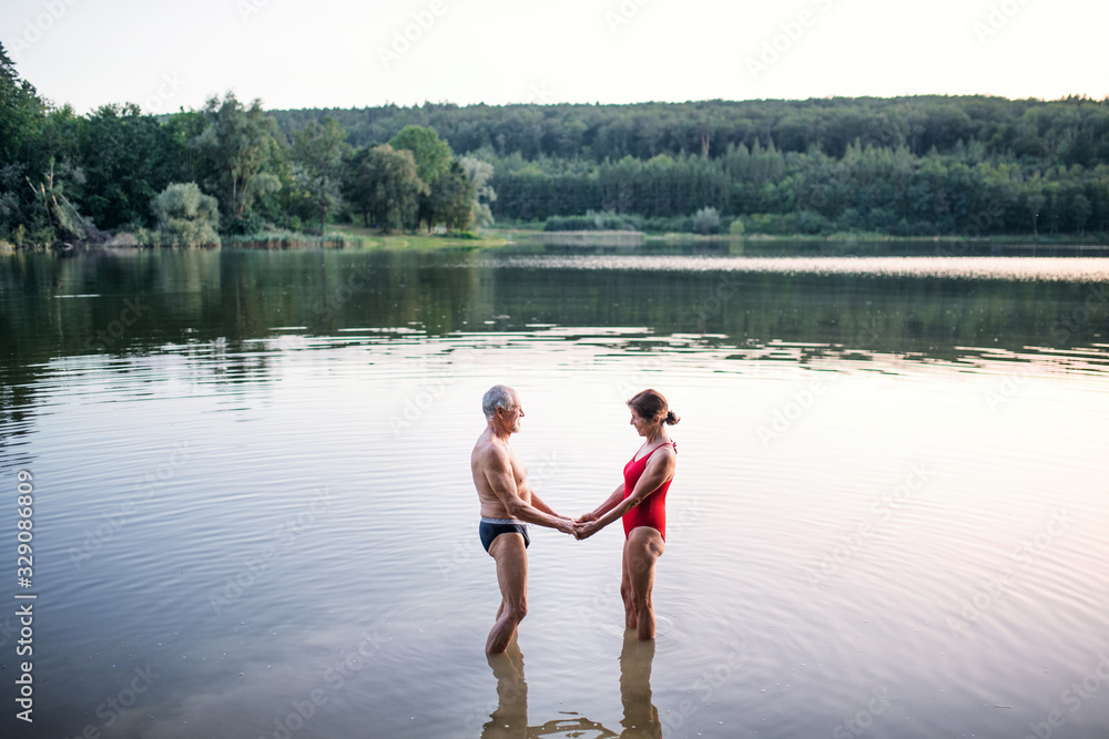 Senior couple in swimsuit standing in lake outdoors before swimming. Senior couple in swimsuit standing in lake outdoors before swimming.