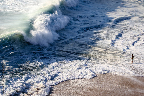onda grande na beira da praia na frente do homem
