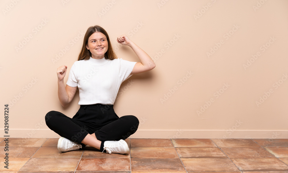 Ukrainian teenager girl sitting on the floor celebrating a victory Ukrainian teenager girl sitting on the floor celebrating a victory