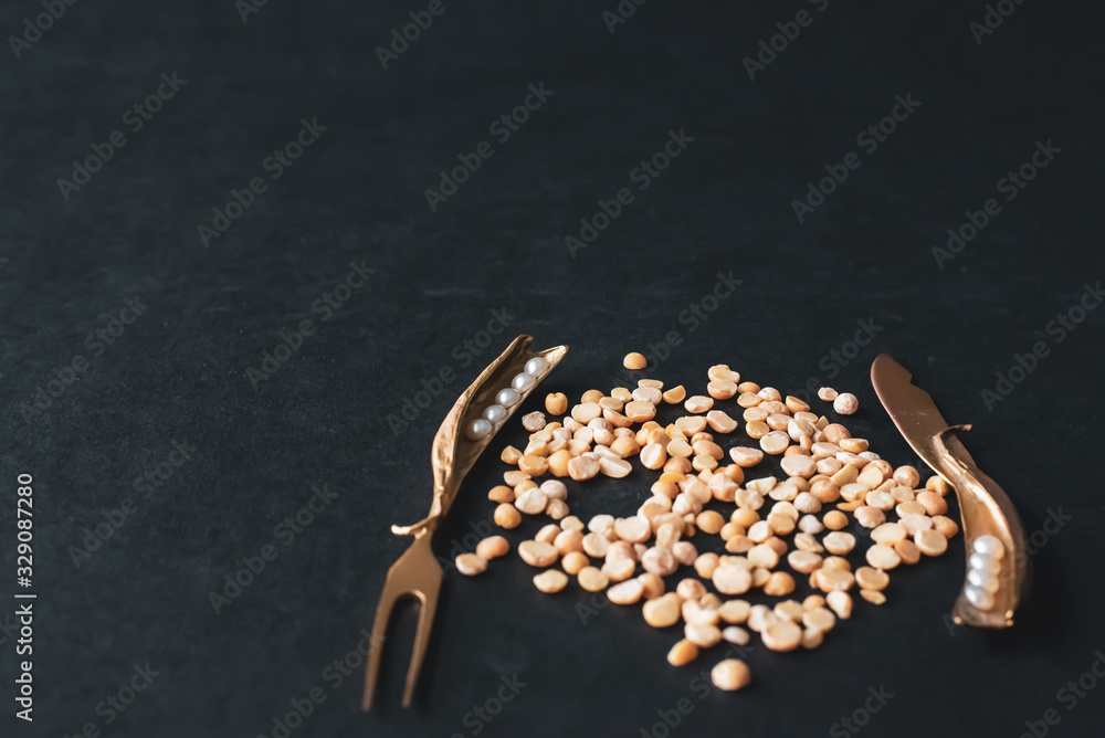 Peas and decorative fork and knife on a dark background. Peas and decorative fork and knife on a dark background.