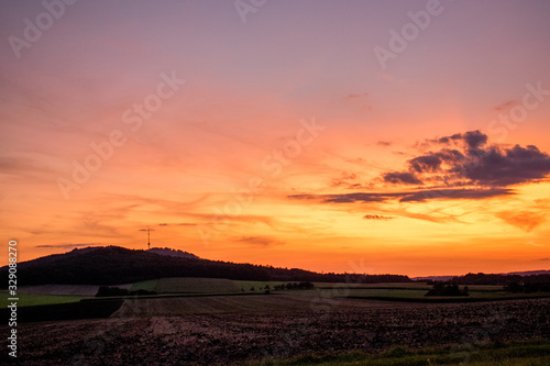 Sonnenübergang über dem Hesselberg in Mittelfranken (Bayern). Der Himmel leuchtet intensiv und farbenreich in verschiedenen Orangetönen.  © Tina Rabus