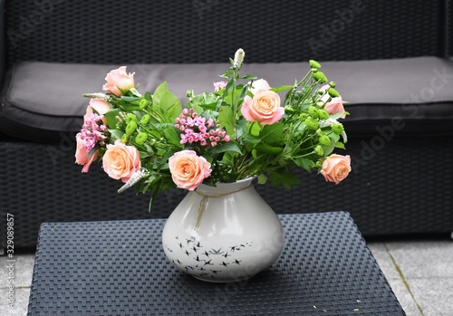 A vase with flolwers on a table in the garden. photo