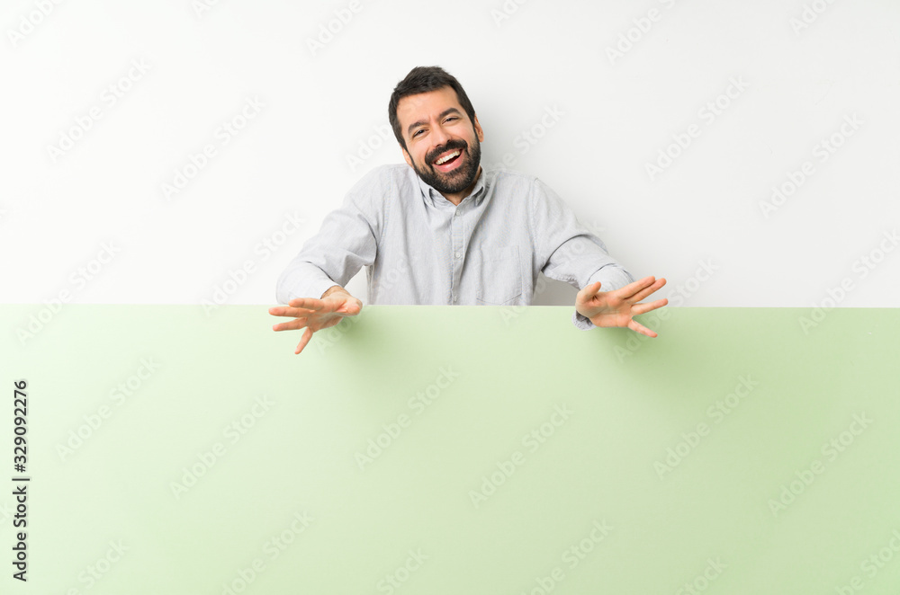 Young handsome man with beard holding a big green empty placard smiling Young handsome man with beard holding a big green empty placard smiling