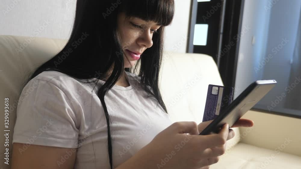 girl makes online lifestyle sale shopping concept with laptop digital tablet. brunette lying on couch watching shop online paying credit card. online shop score girl makes online lifestyle sale shopping concept with laptop digital tablet. brunette lying on couch watching shop online paying credit card. online shop score