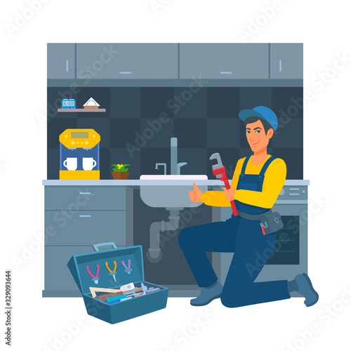 A cheerful worker in a blue uniform and a cap with a pipe wrench in his hand. Kitchen on the background. A repair man. A happy male professional plumber kneels near a sink, showing gesture thumb up.