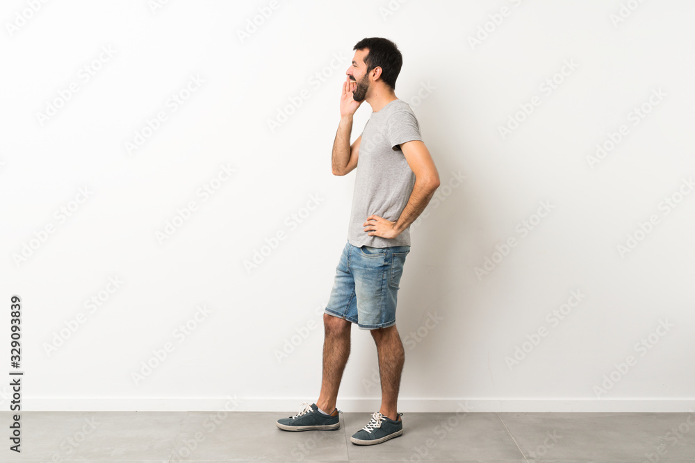 A full-length shot of handsome man with beard shouting with mouth wide open to the lateral A full-length shot of handsome man with beard shouting with mouth wide open to the lateral