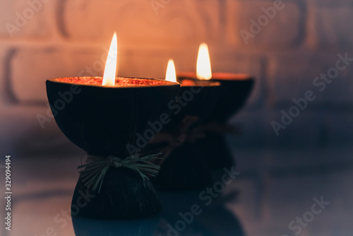 Burning spa aroma candles in coconut shell on a glass white table, cozy home interior.