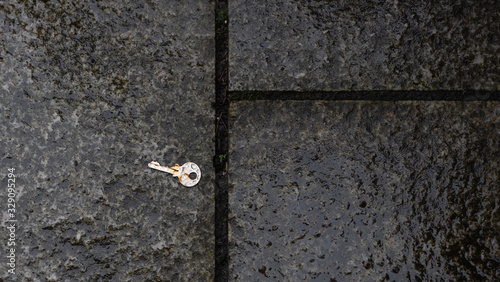 A rusty old lost key on a wet pavement spotted near a bicycle rack © Robyn of Exeter