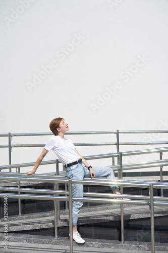Short haired redhead young woman lies on railing in urban center in hot summer day