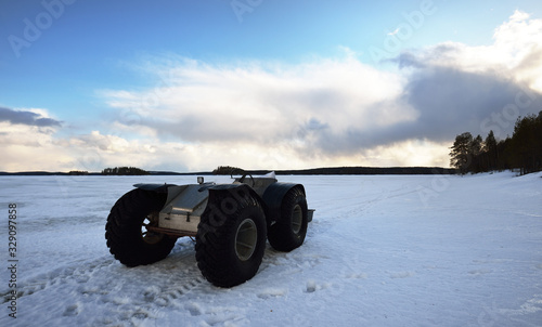 A hand made all terrain vehicle on the snow-covered field at sunset, close-up. Winter country landscape. Karelia North, Lapland, Kuito lake photo