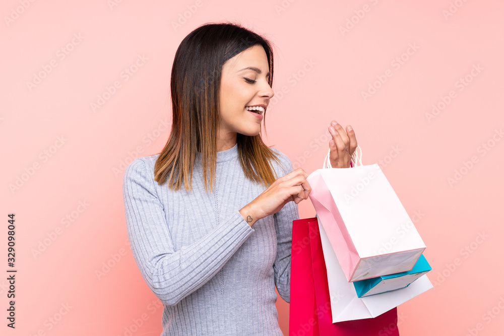 Woman over isolated pink background holding shopping bags Woman over isolated pink background holding shopping bags
