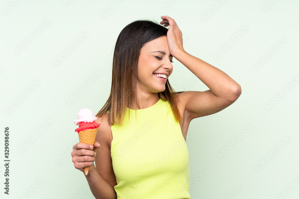 Brunette woman holding a cornet ice cream over isolated green background has realized something and intending the solution Brunette woman holding a cornet ice cream over isolated green background has realized something and intending the solution
