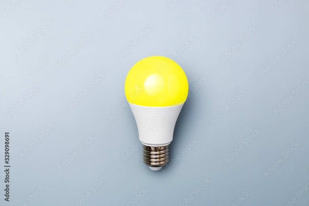 switched on led bulb with yellow light on grey background with copy space for advert. business idea concept switched on led bulb with yellow light on grey background with copy space for advert. business idea concept