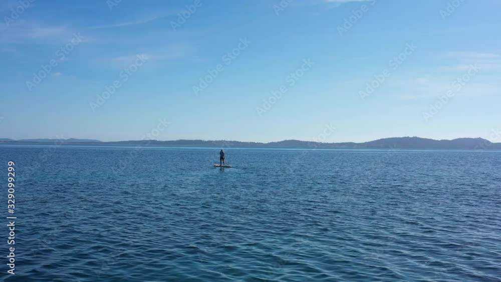 Man stand up paddling aerial shot calm mediterranean sea France Porquerolles island in background Man stand up paddling aerial shot calm mediterranean sea France Porquerolles island in background