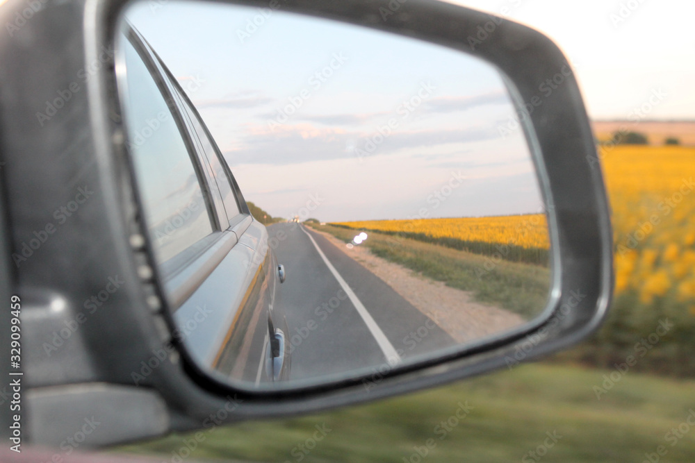 the road is reflected in the side rear-view mirror of the car, close-up