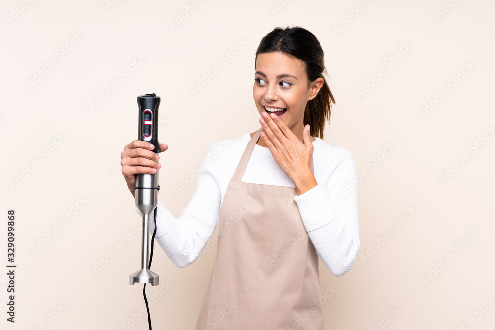 Woman using hand blender over isolated background with surprise and shocked facial expression Woman using hand blender over isolated background with surprise and shocked facial expression