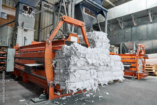 A paper recycling factory plant shredding machine, shredding waste paper into square bails, ready to be pulped and reused. Recycle waste materials to offset pollution and save the planet.