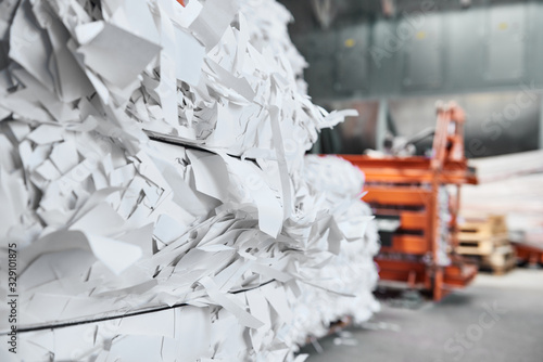 A paper recycling factory plant shredding machine, shredding waste paper into square bails, ready to be pulped and reused. Recycle waste materials to offset pollution and save the planet.