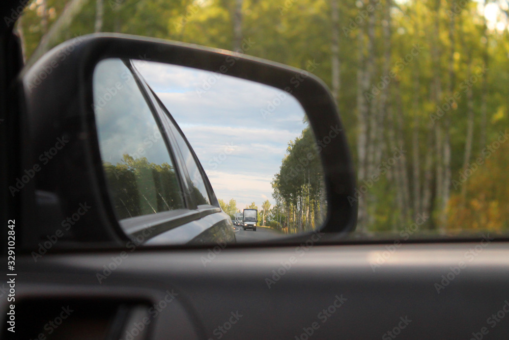 the road is reflected in the side rear-view mirror of the car, close-up