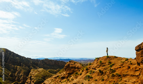 Young girl enjoys the view of valley on top of hill