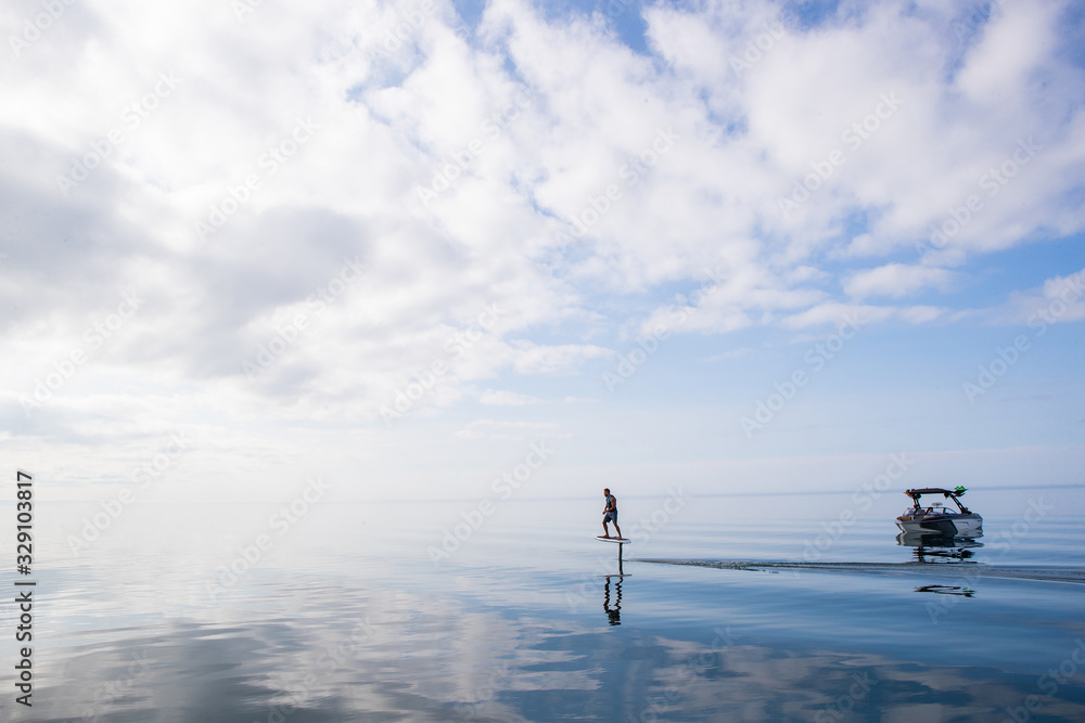 Man riding an electric hydrofoil foil board on a lake with a life jacket
