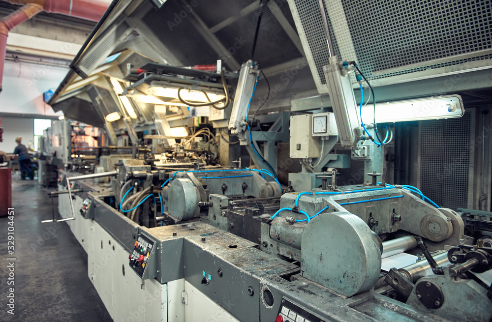 A industrial commercial envelope making machine, making paper envelopes for international distribution. Automated engineering machinery for mass production of paper envelopes.