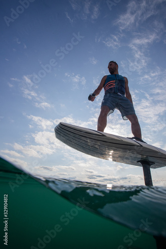 Obraz na płótnie Man riding an electric hydrofoil foil board on a lake with a life jacket w salonie
