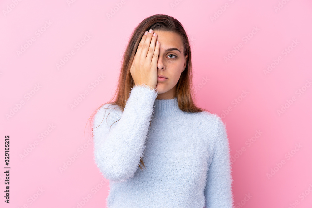 Teenager girl with blue sweater over isolated pink background covering a eye by hand Teenager girl with blue sweater over isolated pink background covering a eye by hand
