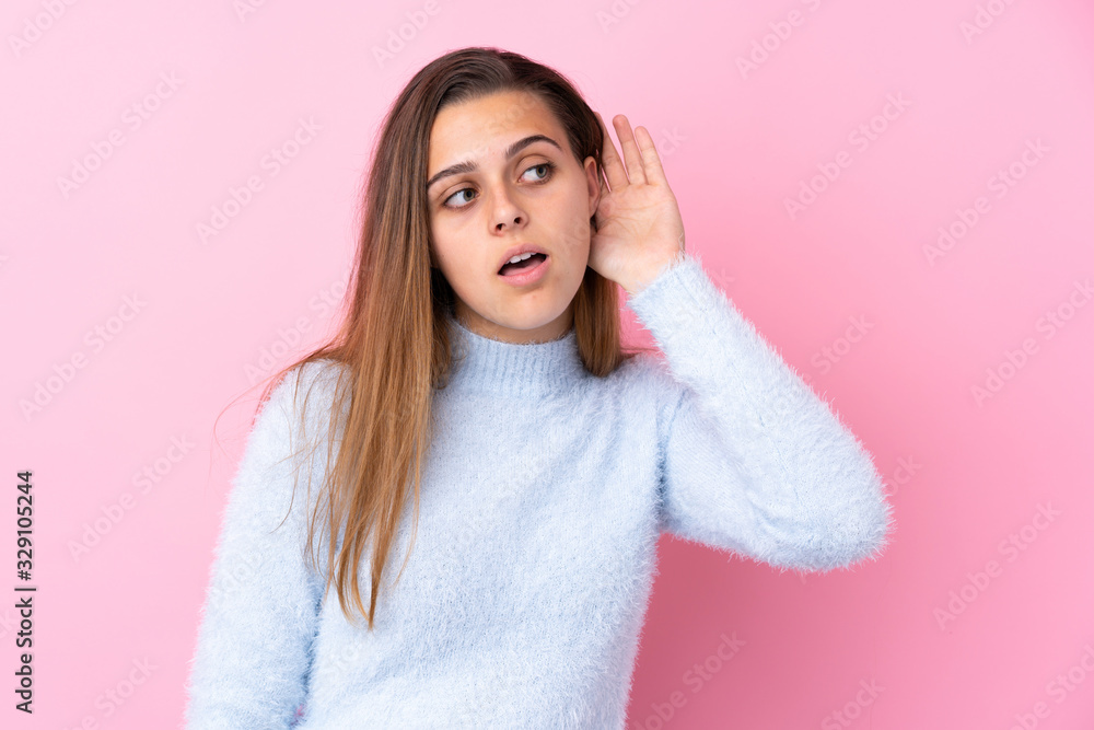 Teenager girl with blue sweater over isolated pink background listening something Teenager girl with blue sweater over isolated pink background listening something