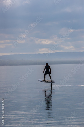 Obraz na płótnie Man riding an electric hydrofoil foil board on a lake with a life jacket w salonie
