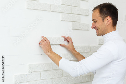 Stylish trendy white ceramic tile with a chamfer on the kitchen wall. Tiler hands in the process of laying white rectangular tiles on bathroom wall. Repair of apartments and bathrooms.