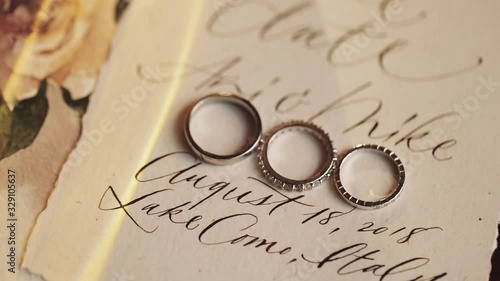 Wedding rings and the bridal engagement ring lie on the card with wedding day invitation, written in the beautiful font