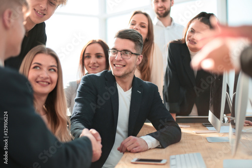 Manager congratulating a young employee in the workplace.