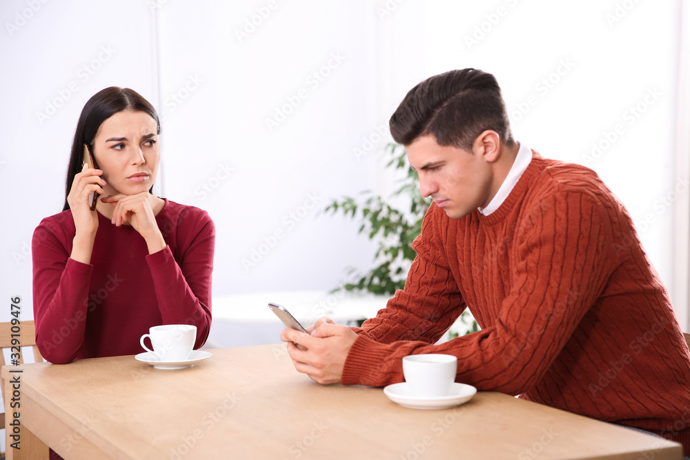 Couple addicted to smartphones ignoring each other in cafe. Relationship problems Couple addicted to smartphones ignoring each other in cafe. Relationship problems