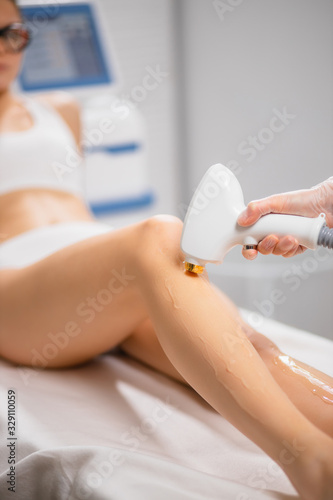 Картината върху платно close-up photo of young woman getting laser hair removal procedure on her legs in modern clinic