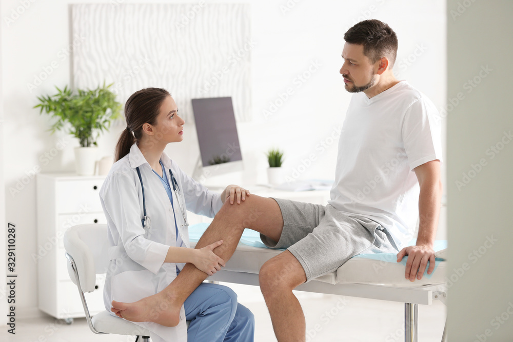 Female orthopedist examining patient's leg in clinic Female orthopedist examining patient's leg in clinic