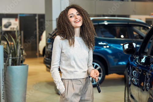 I have made the right choice. awesome young woman standing near the car at the dealership. exitic car. used car for sale,cheap prices, girl has won the car in the lottery photo