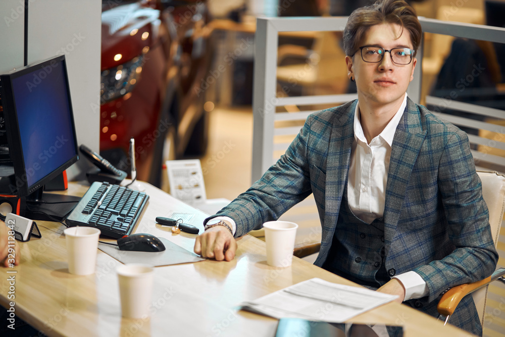 young successful handsome man in glasses sitting at workplace, close up photo. work, job, occupation, working hours. day, he is looking at the camera young successful handsome man in glasses sitting at workplace, close up photo. work, job, occupation, working hours. day, he is looking at the camera