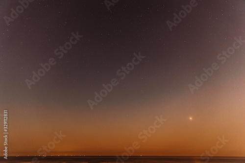 Real Colorful Night Sunset Sky Stars. Natural Starry Sky Above Sea Seascape Ocean Beach. Background