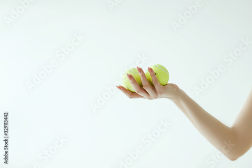 Three tennis balls in woman hand on white background (with clipping path) © Nina