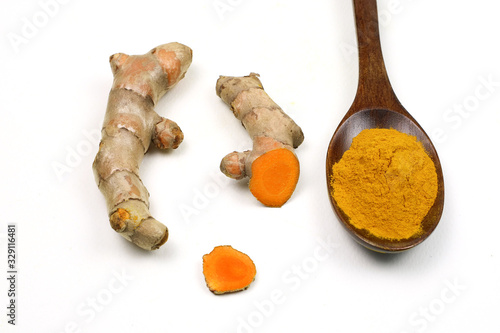 Turmeric powder in a wooden spoon and fresh turmeric roots isolated on a white background is an ingredient in turmeric foods and ingredients in skin care products. Turmeric helps strengthen the skin.