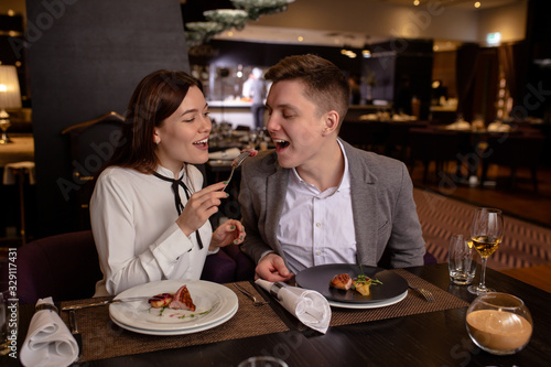 happy young caucasian couple spend their evening in restaurant. beautiful woman and man sit and enjoy meal together. romantic time of couple in restaurant