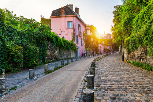 Fototapeta Naklejka Na Ścianę i Meble -  Montmartre district of Paris. Houses on narrow road in Montmartre district of Paris. View of cozy street in quarter Montmartre in Paris, France. Architecture and landmarks of Paris. Postcard of Paris.